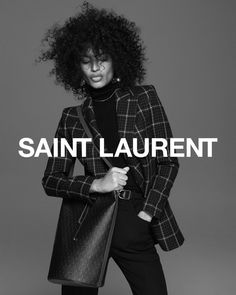 a woman in black and white is holding a handbag with the words saint laurent on it