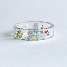 Custom wish Care Bear ring Please make sure to size your finger I will no longer be accepting exchanges as I have to pay for the shipping to send the new size.  Thank you ♥️ & I hope you understand  This adorable ring is so unique.  I made this ring for a customer and she was in love with this item.  So I decided to post it as a listing.  I can't wait to make yours! This ring is unique so no two are the same. The smaller the ring size you may only see half of the belly design Shipping says 5-7 days however most of the time I get the order out within a few days. Colors may be a little lighters however I have and am working on adding non edited photos and videos to all care Bear listings. Very dainty and unique Clear Plastic Jewelry For Gifts, Clear Plastic Jewelry As A Gift, Clear Plastic Jewelry Gift, Playful Plastic Jewelry For Gifts, Playful Plastic Jewelry As Gift, Playful Plastic Jewelry Gift, Cute Plastic Jewelry For Gifts, Whimsical Adjustable Rings, Fun Clear Jewelry As Gift