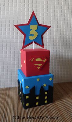 a birthday cake made to look like superman's box with the number 3 on top