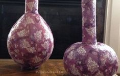 two purple vases sitting on top of a wooden table next to a fire place