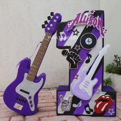 two purple guitars are sitting next to each other in front of a sign with the word rock and roll written on it