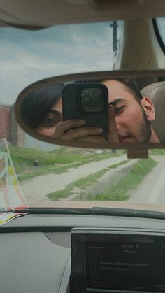 a man and woman taking a selfie in the rear view mirror