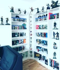 a living room filled with lots of books and action figures on top of white shelves