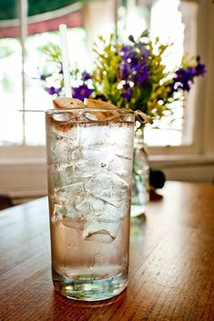 a glass filled with ice sitting on top of a wooden table