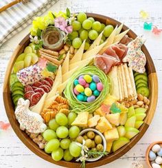 a wooden bowl filled with lots of different types of cheese and crackers on top of a table