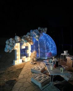 an outdoor party setup with balloons and lights in the shape of letters on display at night