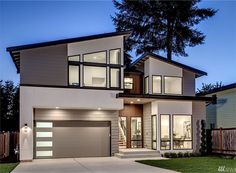 a modern home at night with large windows and two car garages on the front