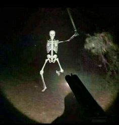 a skeleton is walking in the dark with its arms out and it's shadow on the ground