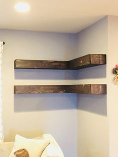 two wooden shelves on the wall above a bed