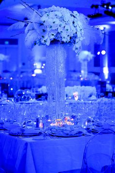 a tall vase filled with white flowers sitting on top of a table covered in candles