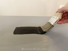 a person is holding a paint brush over the top of a white table with black strips on it