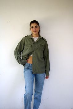 This awesome vintage green military shirt/jacket is nicely broken in, and features a button-up design with pockets. Made from cotton, it includes ventilation openings under the arms. Unisex and suitable for both men and women, aside from minor signs of wear, good vintage condition, clean ready to wear, this piece is a versatile and stylish addition to any wardrobe. ** Model is 5'7" and size S for reference **      Approximate size:  M/L- please refer to the measurements. M E A S U R E M E N T S -were taken with garments laying flat, please double where necessary. ------------------------♥-------- Length:  27"-69cm Armpit to Armpit: 23"-59cm (closed) Shoulder to Shoulder: 19.5" - 50cm Sleeve: 22.5"- 57cm. ---------------------------------------------- All items are vintage pieces, previousl Green Collared Utility Jacket With Pockets, Vintage Relaxed Fit Button-up Shacket, Green Button-up Utility Jacket With Flap Pockets, Vintage Green Utility Jacket For Work, Khaki Collared Tops With Cargo Pockets, Vintage Green Utility Jacket For Fall, Retro Khaki Cotton Utility Jacket, Military Button-up Utility Jacket With Cargo Pockets, Military Green Utility Jacket With Button Closure