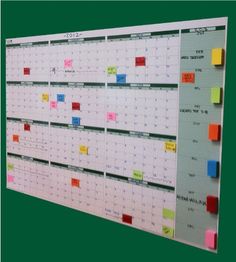 a wall mounted calendar with sticky notes on the front and back of it, as well as colored post - it notes