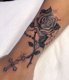 a black rose and cross tattoo on the left arm, with beads around it's ankles