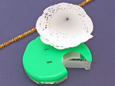 a green and white object sitting on top of a purple surface next to a string