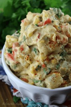 a white bowl filled with potato salad on top of a wooden table next to lettuce