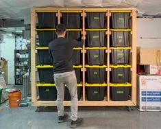 a man standing in front of a shelf filled with plastic bins