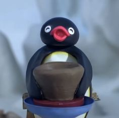 a toy penguin sitting on top of a bowl