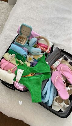 an open suitcase filled with lots of clothes and shoes on top of a white bed