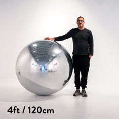 a man standing in front of a shiny ball with his hands on the back of it