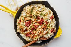 a skillet filled with chicken, cheese and sauce on top of a yellow plate