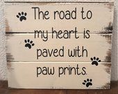 a wooden sign that says the road to my heart is paved with paw prints on it