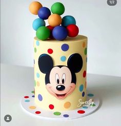 a mickey mouse cake with multicolored balls on it's top and face