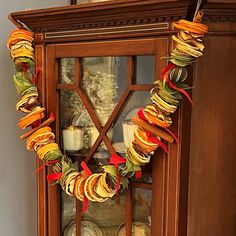 an old china cabinet decorated with fall leaves and ribbons for the holiday season is ready to be displayed