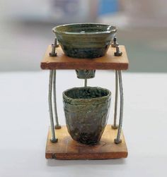 two bowls sitting on top of each other on a wooden stand with metal bars around them