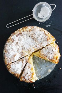 a pie with powdered sugar on top and two serving utensils next to it