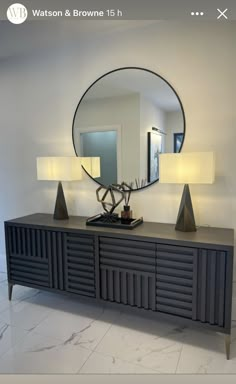 a large mirror sitting on top of a dresser next to two lamps and a lamp