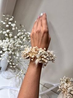 a woman's hand with two bracelets on her wrist and flowers in the background