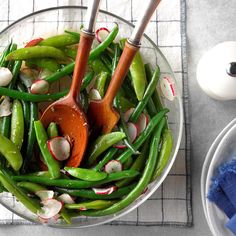 a glass bowl filled with green beans and carrots