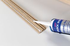 a bottle of glue sitting on top of a wooden shelf next to some wood sticks