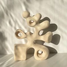 a white sculpture sitting on top of a table next to a white wall in the background