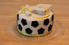 a cake decorated with black and white designs on a glass platter next to a wooden table