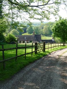 a dirt road with a wooden fence and houses in the background