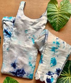 two pieces of clothing sitting on top of a wooden table next to green leafy plants