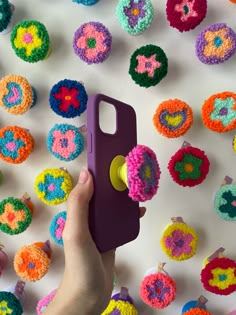 a person holding a purple object in front of colorful crocheted donuts on a white surface