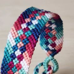 a crocheted bracelet is displayed on a wooden surface, with the clasp undone