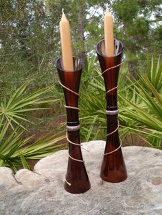 two brown vases sitting on top of a rock next to each other with candles in them