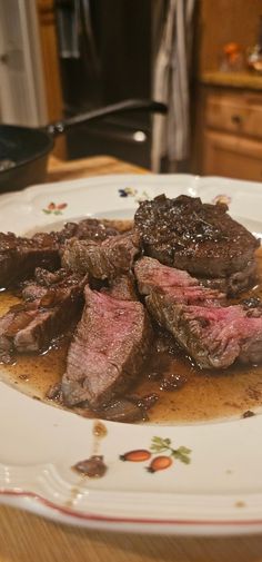 a white plate topped with steak and gravy on top of a wooden table