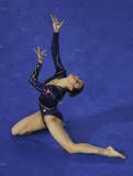 a woman in a black leotard doing a handstand on a blue floor