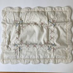 a white table cloth with embroidered flowers on it