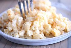 a white plate topped with macaroni and cheese covered in gravy next to a fork