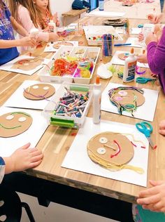 a group of children sitting at a table making crafts with paper plates and scissors on it