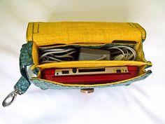 an open yellow purse on a white surface with wires and cords in the bottom compartment