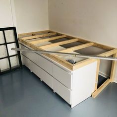 an unfinished bed frame with drawers in the middle