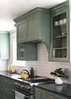 a kitchen with green cabinets and black counter tops