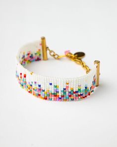 Handmade Miyuki Confetti Celebration Bracelet By The Gem Stories Celebrate in style with the vibrant Miyuki Confetti Celebration Bracelet, a colorful and joyful piece perfect for adding a playful touch to any outfit. Handwoven with Miyuki Delica beads in a mix of bright, cheerful colors, this bracelet evokes the excitement and fun of a festive celebration.  The splash of colors is beautifully set against a clean white backdrop, making it the ultimate statement piece for any occasion. Details: Ma Miyuki Delica Beads Free Pattern, White Bangle Friendship Bracelets With Colorful Beads, White Beaded Bangle Bracelets For Festival, White Bangle Friendship Bracelets For Festival, Multicolor Jubilee Beaded Bracelets For Friendship, Playful White Adjustable Bracelets, Playful Adjustable White Bracelets, Multicolor Jubilee Bracelet Jewelry For Festivals, Multicolor Jubilee Bracelet For Festivals